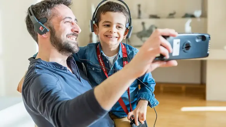 Vader en zoon met hoofdtelefoons maken een selfie tijdens een audiotour