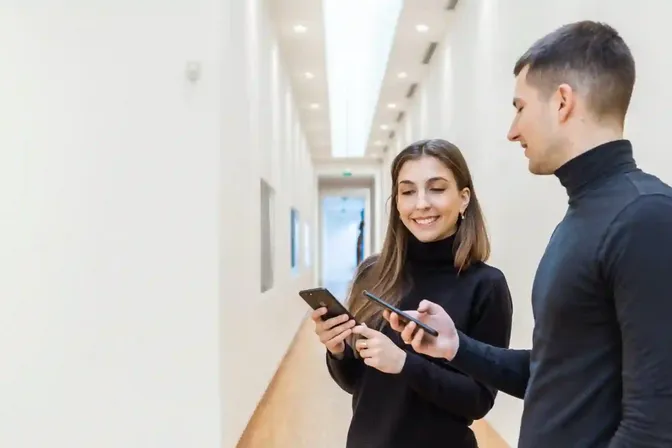 Twee bezoekers gebruiken een museumapp op hun smartphone