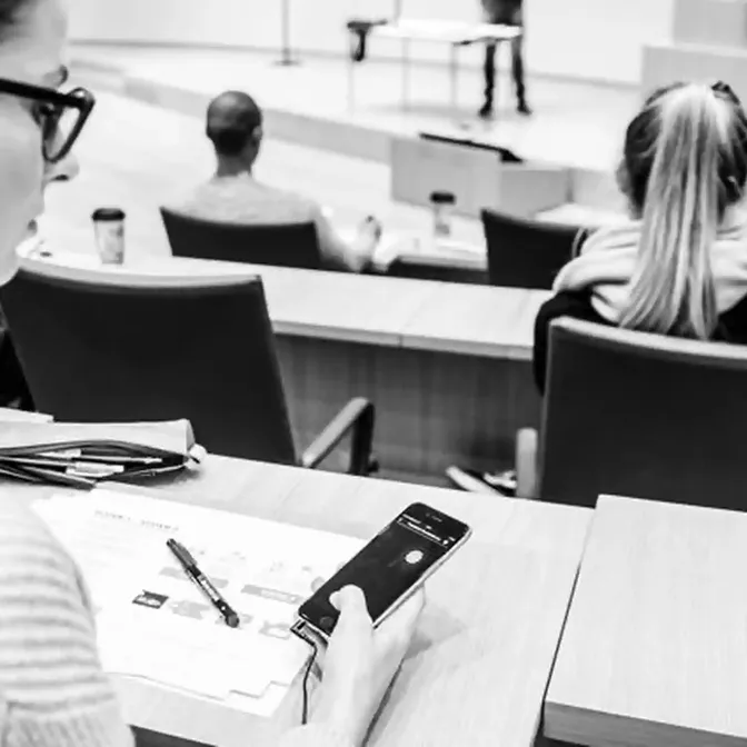 Bezoekers luisteren via hun smartphone naar een live stream in een collegezaal