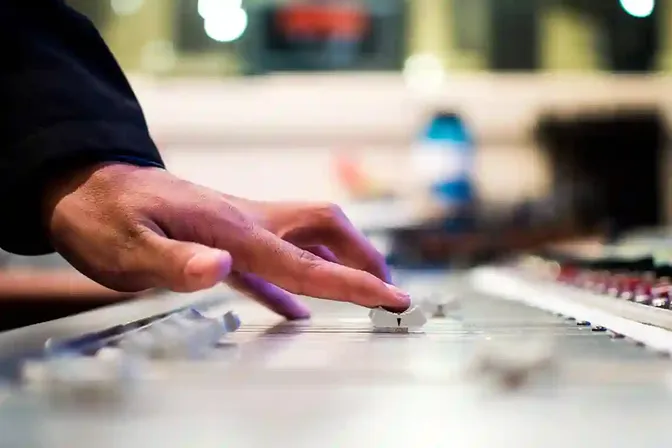 Hand bedient een mengpaneel tijdens de productie van een audiotour
