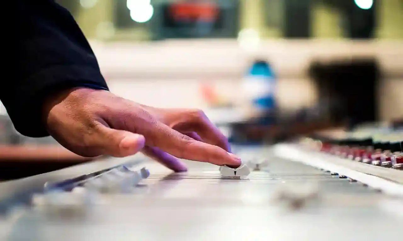Hand bedient een mengpaneel tijdens de productie van een audiotour