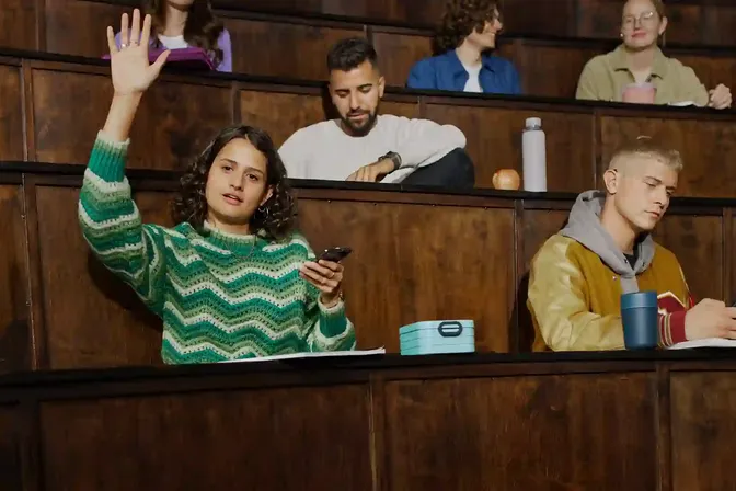 Studenten in een collegezaal luisteren via MobileConnect op hun smartphone