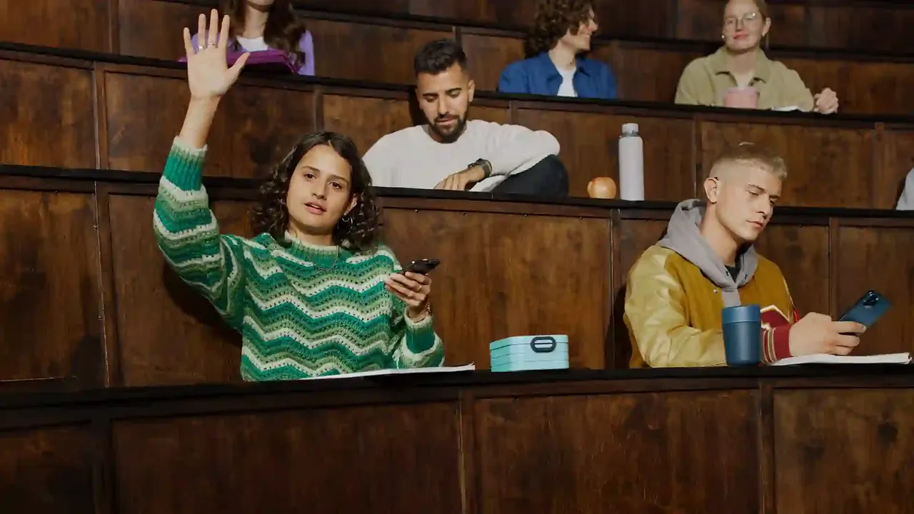 Studenten in een collegezaal luisteren via MobileConnect op hun smartphone