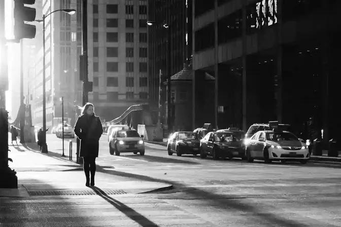 Iemand loopt alleen door een zonnige straat in de stad
