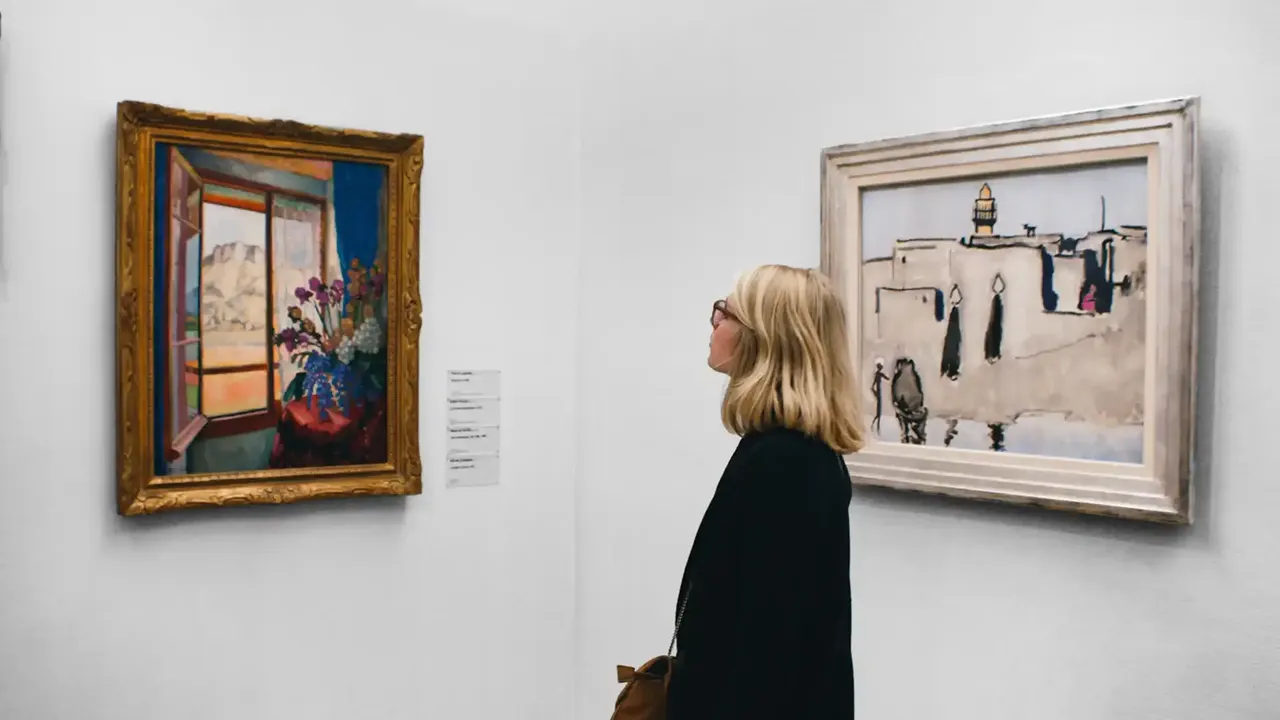 Bezoekster bekijkt schilderijen in een museumzaal