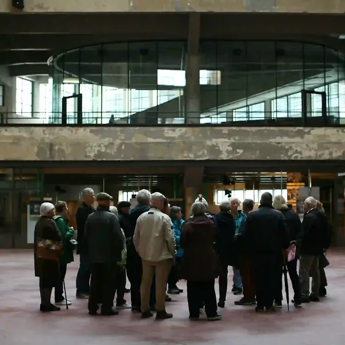 Groep bezoekers luistert naar een rondleider in een fabriekshal