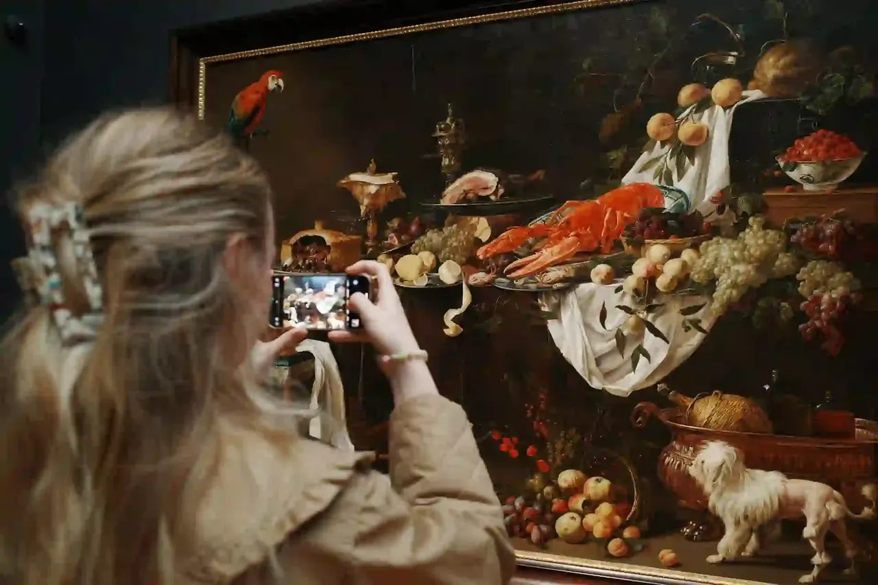 Bezoekster fotografeert een stilleven met haar smartphone in een museum
